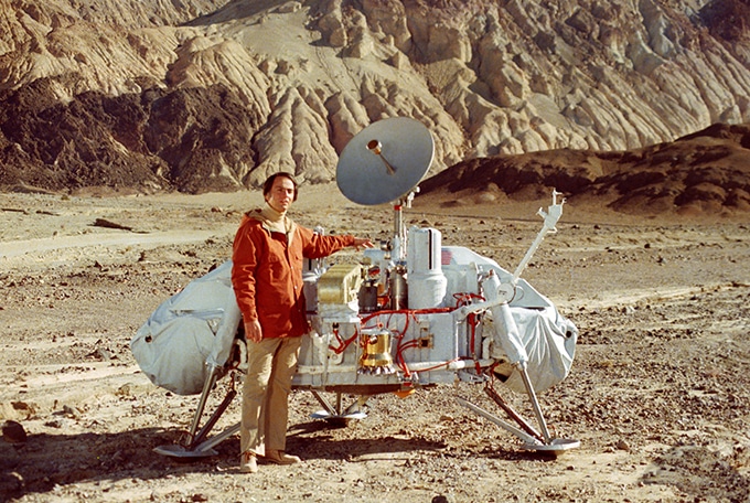 Astronomen og astrobiologen Carl Sagan (1934-1996) står her foran en model af Viking-landingsmodulet i Death Valley i Californien. Viking 1 var en amerikansk rumsonde, der blev opsendt mod Mars den 20. august 1975. Den bestod af både en orbiter og en lander. Orbiteren kredsede om Mars og tog billeder, mens landeren foretog en blød landing på planetens overflade den 20. juli 1976. Viking 1’s lander fungerede i flere år og sendte mange fotos og data tilbage til Jorden, bl.a. fra Labeled Release-eksperimentet, hvis data stadig er gådefulde og skaber videnskabelige diskussioner. Det er en af de røde tråde i bogen ”Vores levende univers”. (Foto: NASA/JPL)